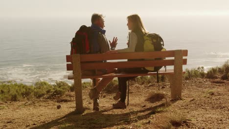 active senior couple sitting on bench in forest