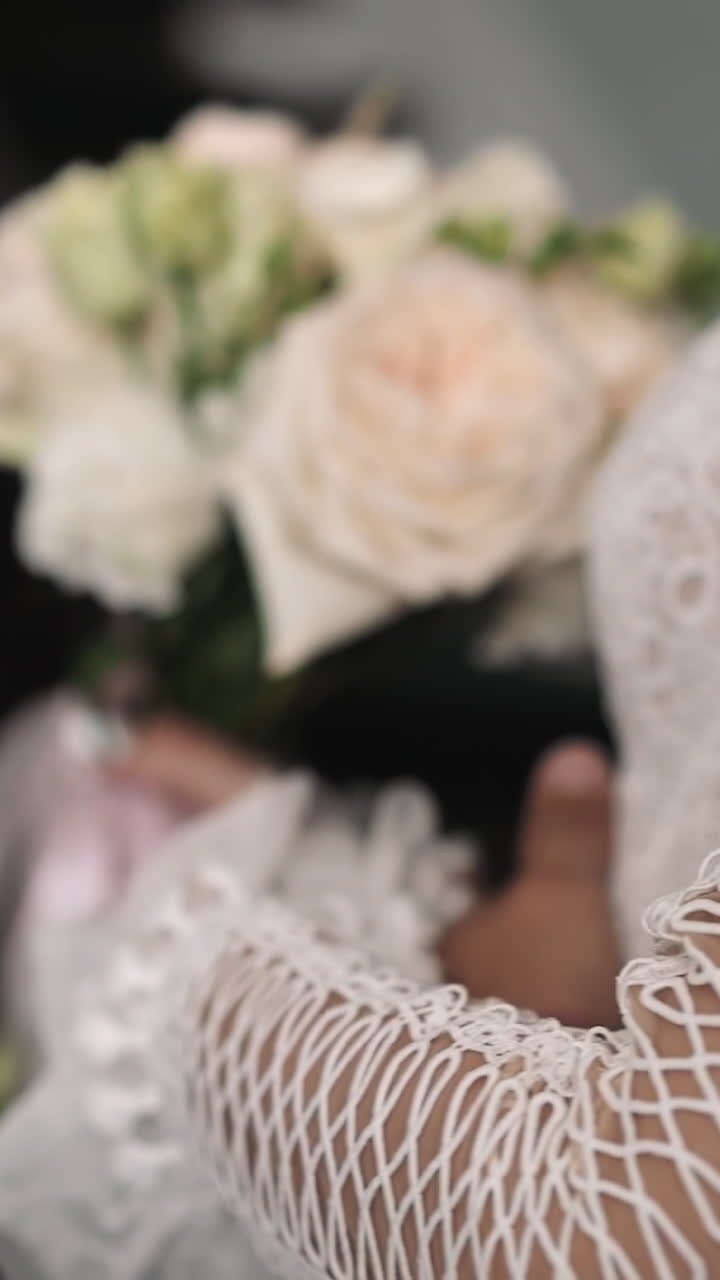 Groom hugs beloved bride in vintage dress holding bouquet on staircase closeup slow motion. Young family at bridal ceremony. Love and affection