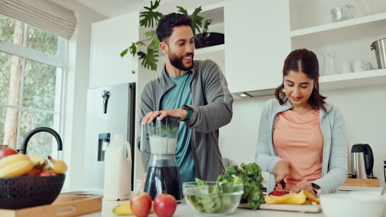Couple preparing healthy smoothie and cutting vegetables in the kitchen