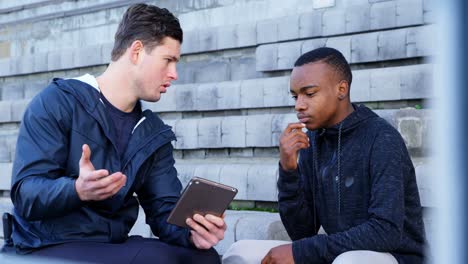 two disabled athletics discussing over digital tablet 4k