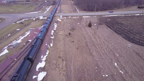 an aerial over an oil train with tanks cars moving rapidly down tracks