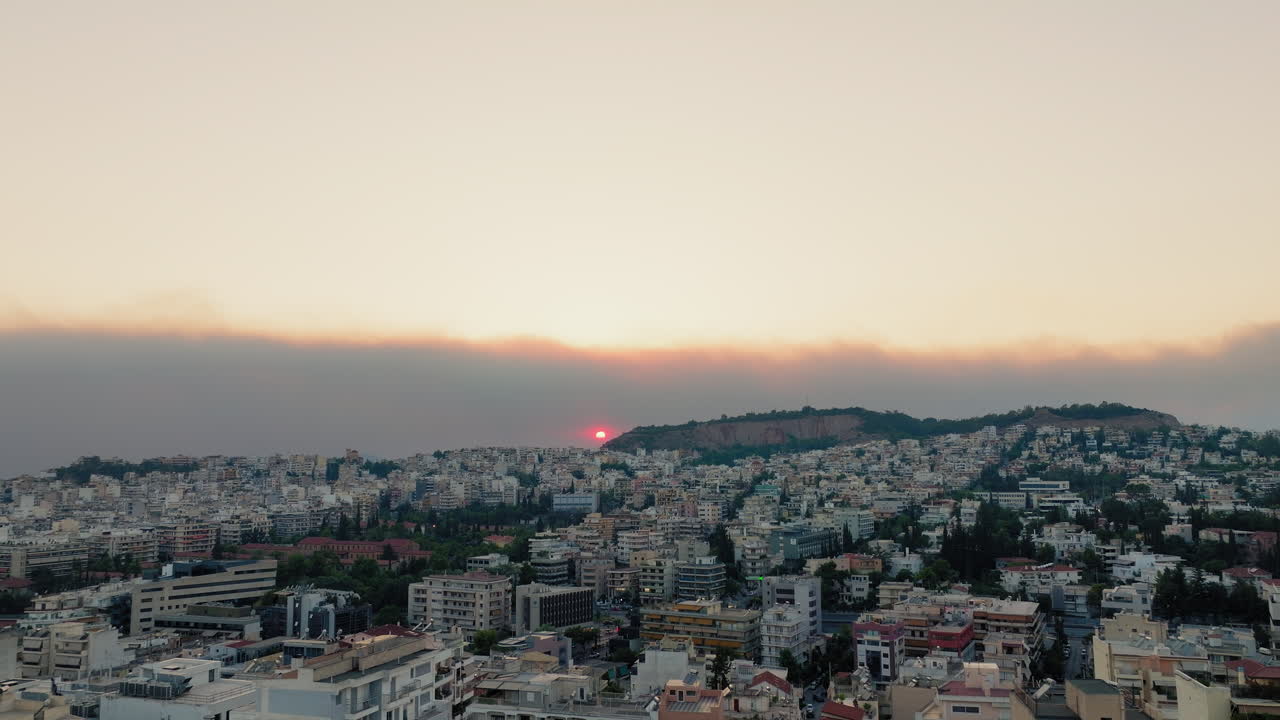 Thick wildfire smoke hangs above Athens skyline as sun sets through hazy sky