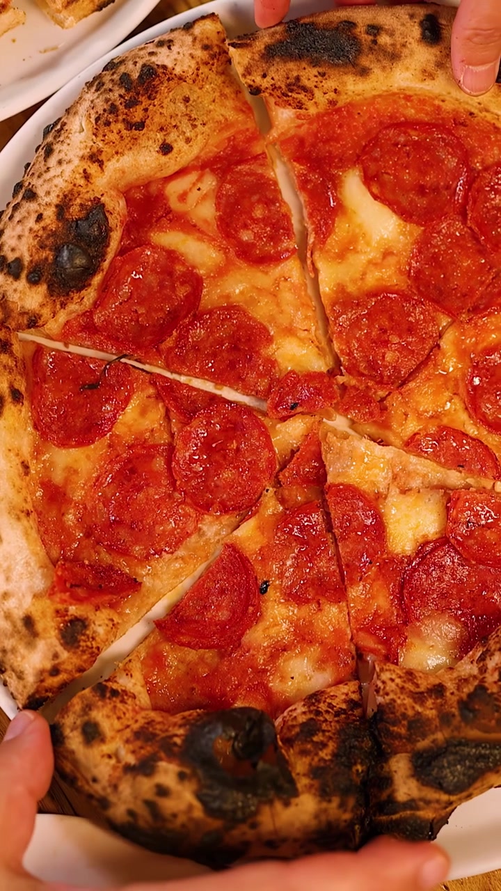 Vista dall'alto di persone che condividono una pizza napoletana a lievitazione naturale durante un incontro conviviale.