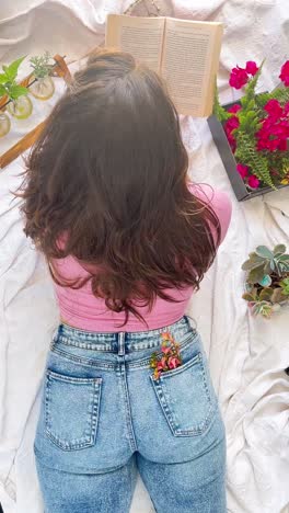 woman reading a book outdoors with flowers and plants