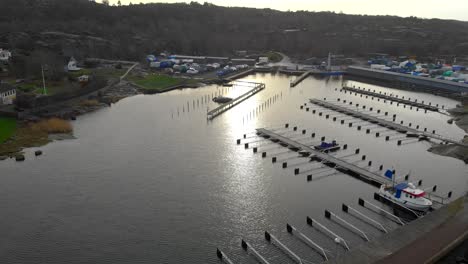 Aerial-view-of-small-harbor-with-few-boats-at-docks,-zooming-shot