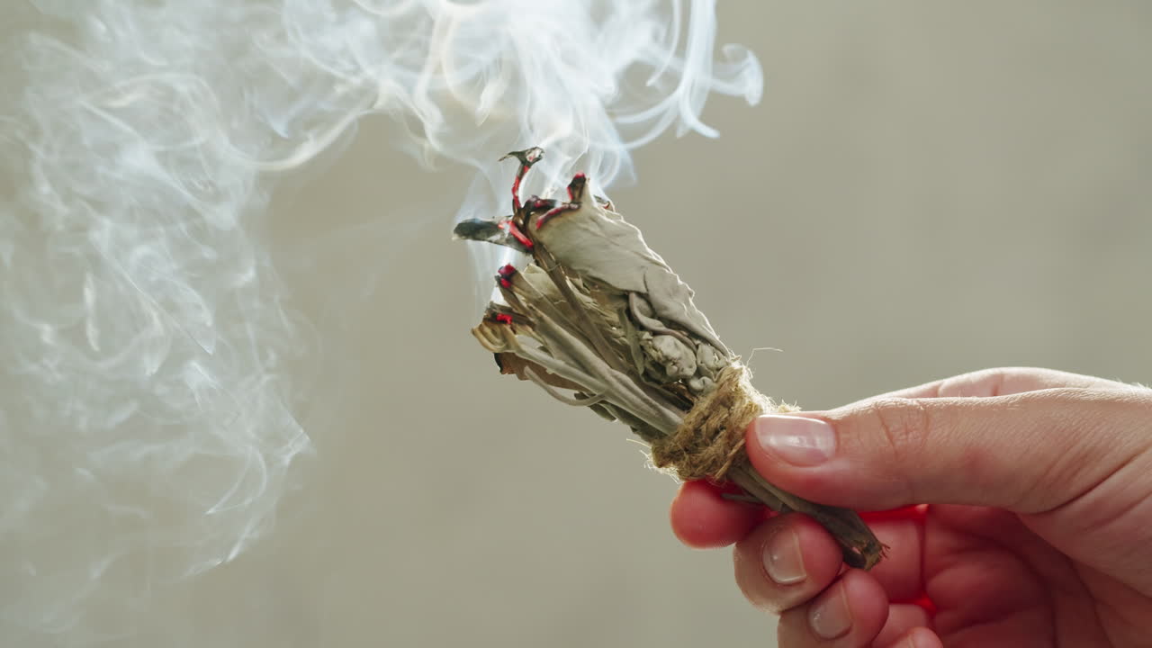 Person holding Palo Santo wood stick in hand, aromatic Palo Santo burning on black background, smoke spreading around, slow motion video clip, high quality 4k close up footage. High quality 4k footage