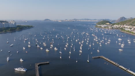 wide aerial footage of a harbor filled with anchored sailboats in botafogo bay and rio de janeiro brazil