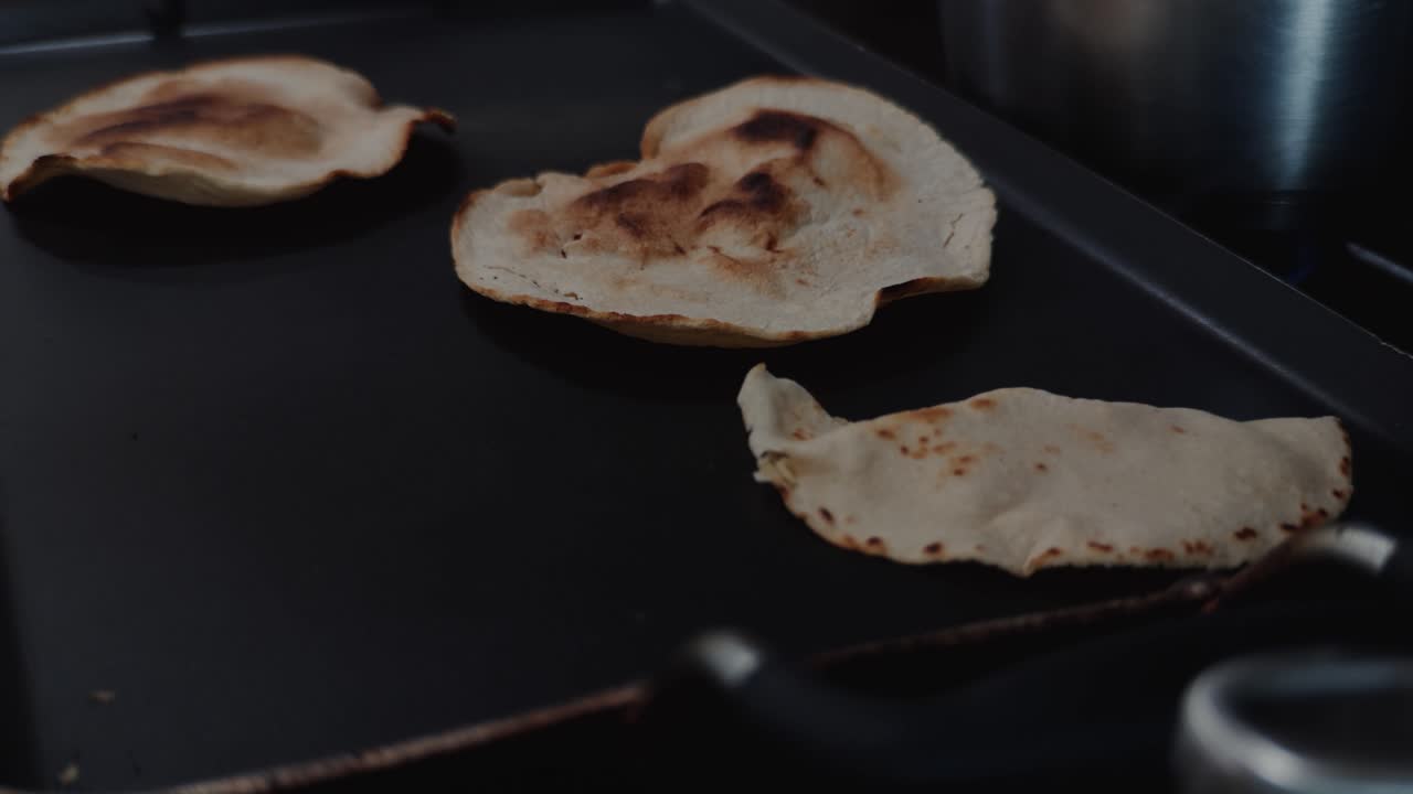 Pan out reveal shot of hom cooked tortillas and beans on a stove.