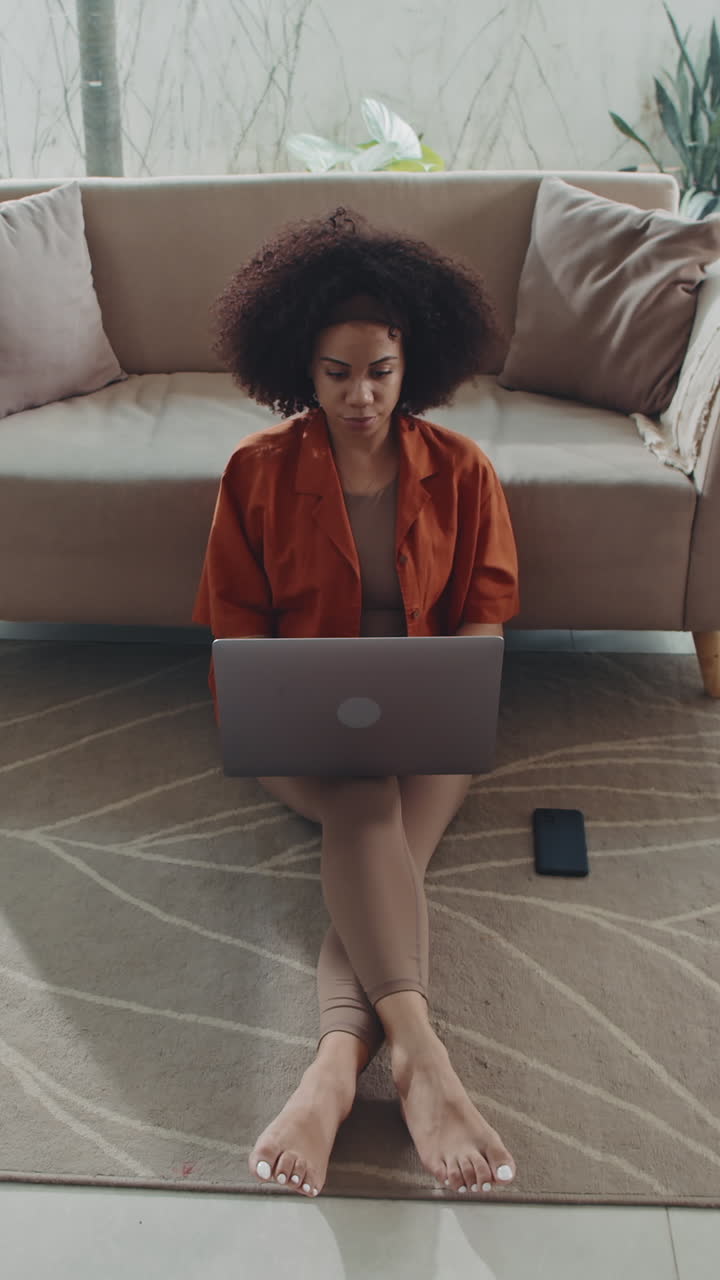 Businesswoman Sitting on Floor Using Laptop at Home