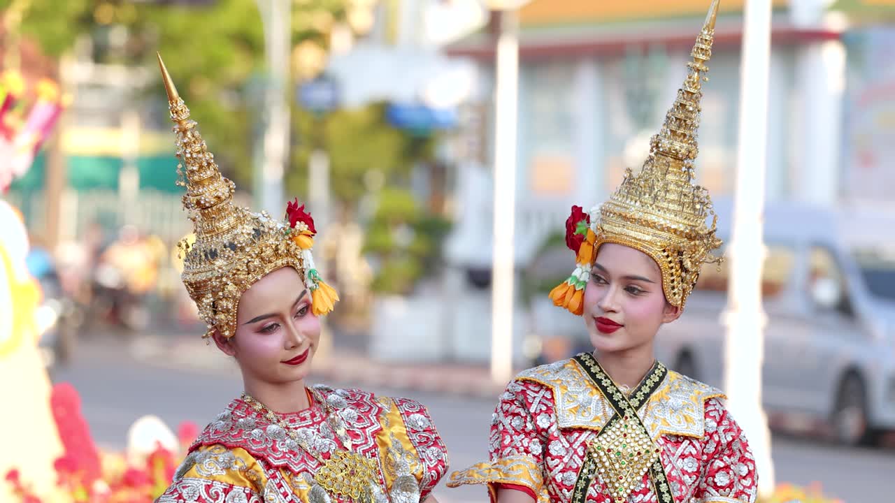 Due ballerine Khon con elaborati copricapi dorati eseguono movimenti tradizionali all'aperto a Bangkok