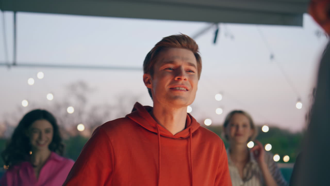 웃는 남자 테일을 주문하는 저녁 바 테라스 클로즈업. 다양한 소녀들이 오고 있습니다.