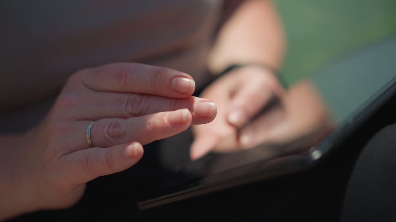 Close up of lady gently sliding through phone screen outdoors under warm sunlight, soft focus showing relaxed motion, symbolizing calm communication, connection