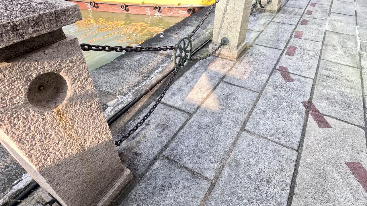 Traditional riverboat moves along Singapore riverfront, modern skyline and architecture in bright daylight
