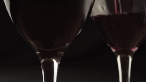 Pouring-wine-two-glasses-dark-background-close-up-shot