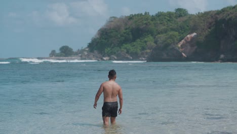 man walking in the shallow water at beach