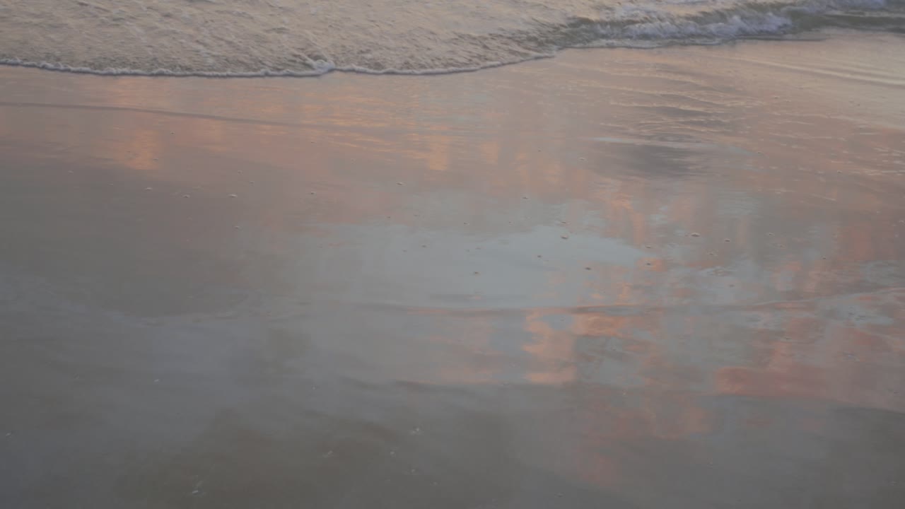 Rolige bølger på en sandstrand ved solopgang fremkalder fred og ro