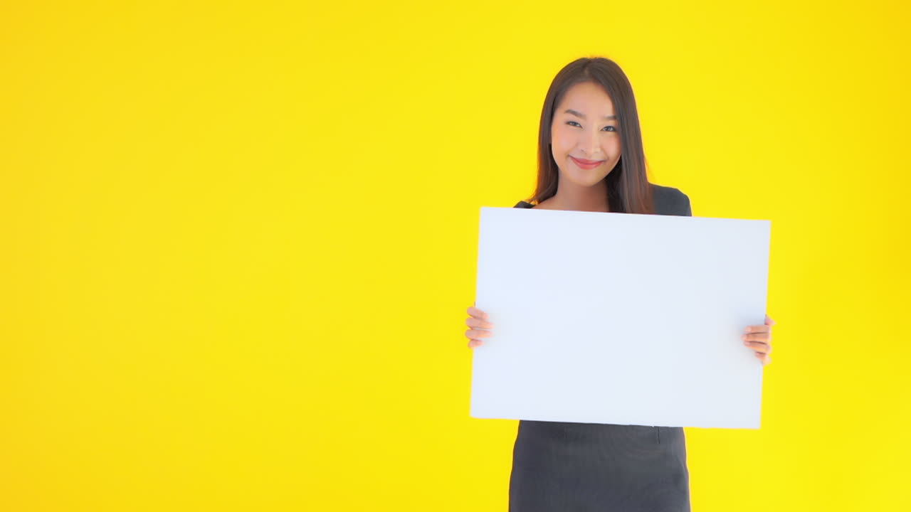 A young cute Asian woman holds up an empty template posterboard. Copy space