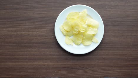 Top-view-of-child-hand-pick-chips-on-table-,