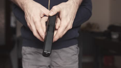 padre enseñando a su hijo cómo cargar una pistola de juguete de nueve milímetros réplica perfecta en casa de cerca