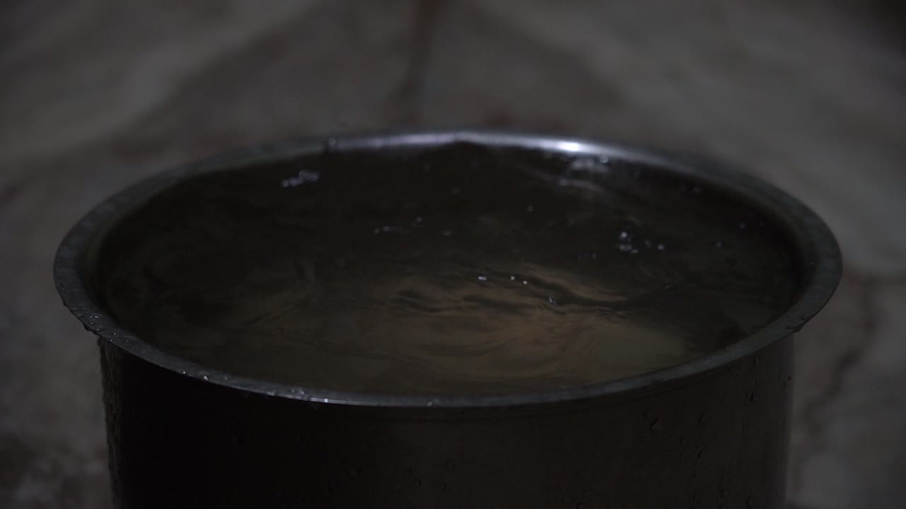 el techo de la casa goteando durante las fuertes lluvias y llenando un utensilio mantenido debajo de él