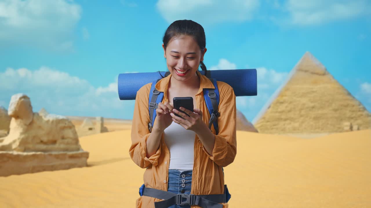 Asian Female Hiker With Mountaineering Backpack Enjoy Using Smartphone While Traveling In Pyramid Of Giza