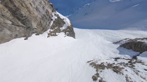 Stunning-aerial-fpv-race-drone-dive-down-snowy-mountain-range-in-Switzerland