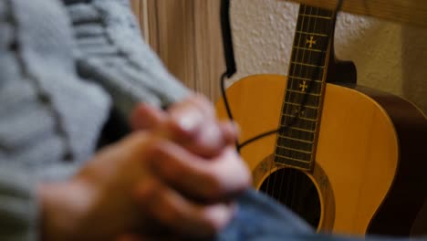 hands folded, person sitting next to a guitar