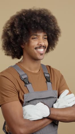 portrait of a smiling man with an afro and mustache wearing overalls and gloves