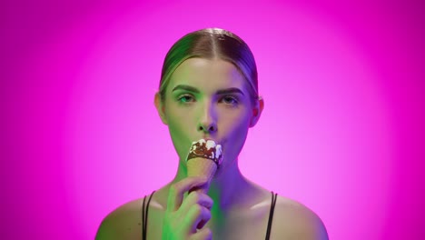 una joven blanca rubia come helado en un fondo infinito de estudio.