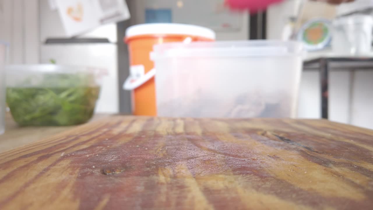 Freshly cooked meat on a wooden board, clamped with red kitchen tongs