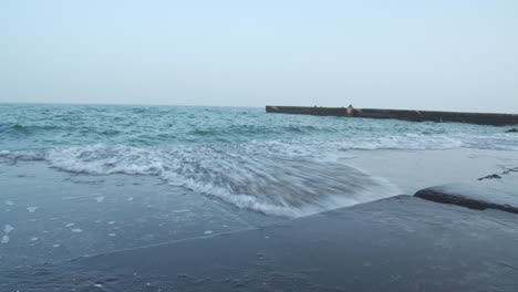 low-angle-shot-of-waves-crashing-against-the-concrete,-the-black-sea-is-dark,-the-day-is-gloomy-and-we