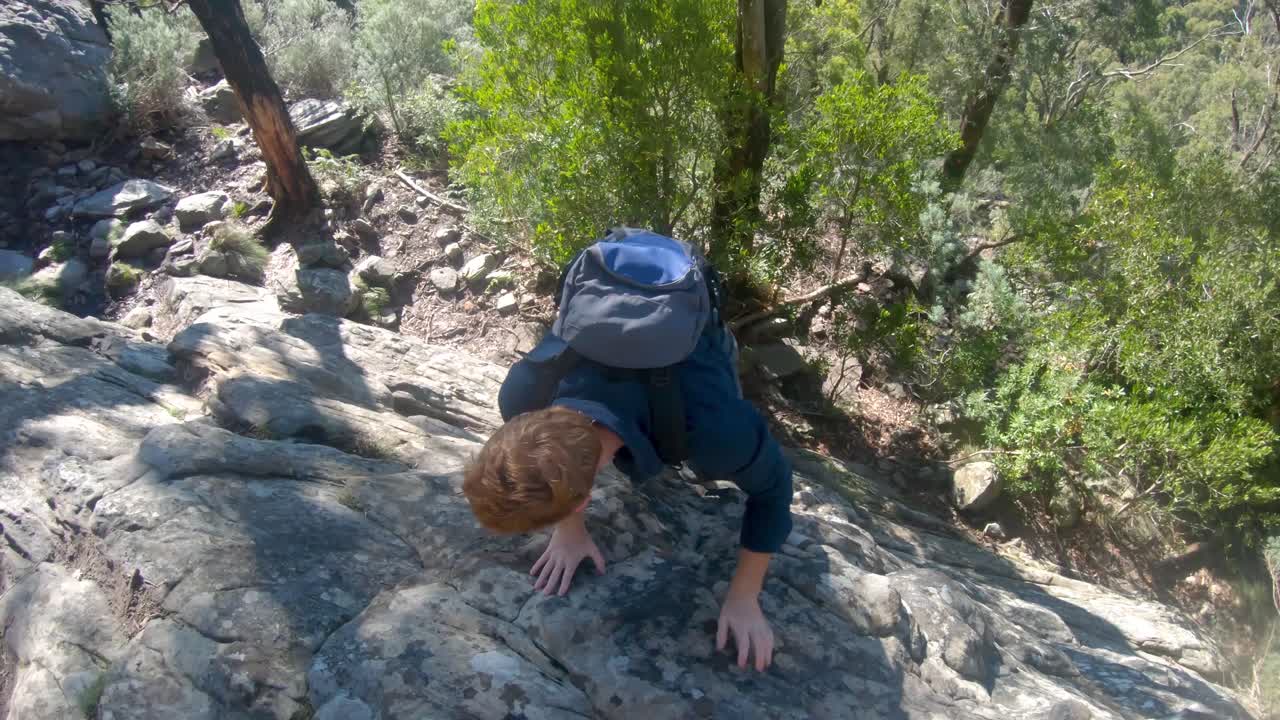 una toma en cámara lenta de un hombre jengibre escalando una pequeña roca vertical en el bosque australiano