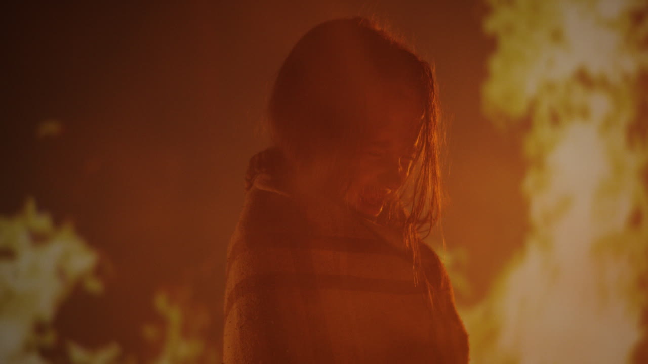 Girl Wrapped in Blanket Against a Backdrop of Flames