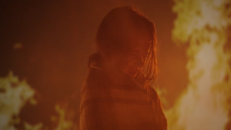 girl wrapped in blanket against a backdrop of flames