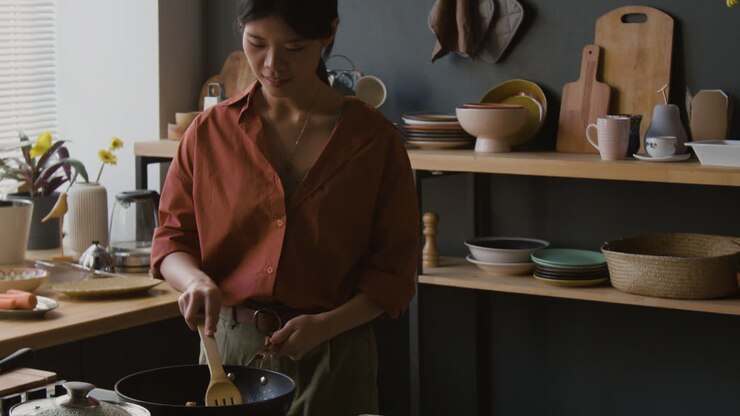 Donna che cucina stir-fry in una cucina moderna.