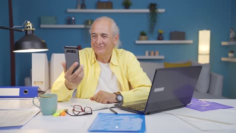 home office worker old man talking on the phone facetime happily.
