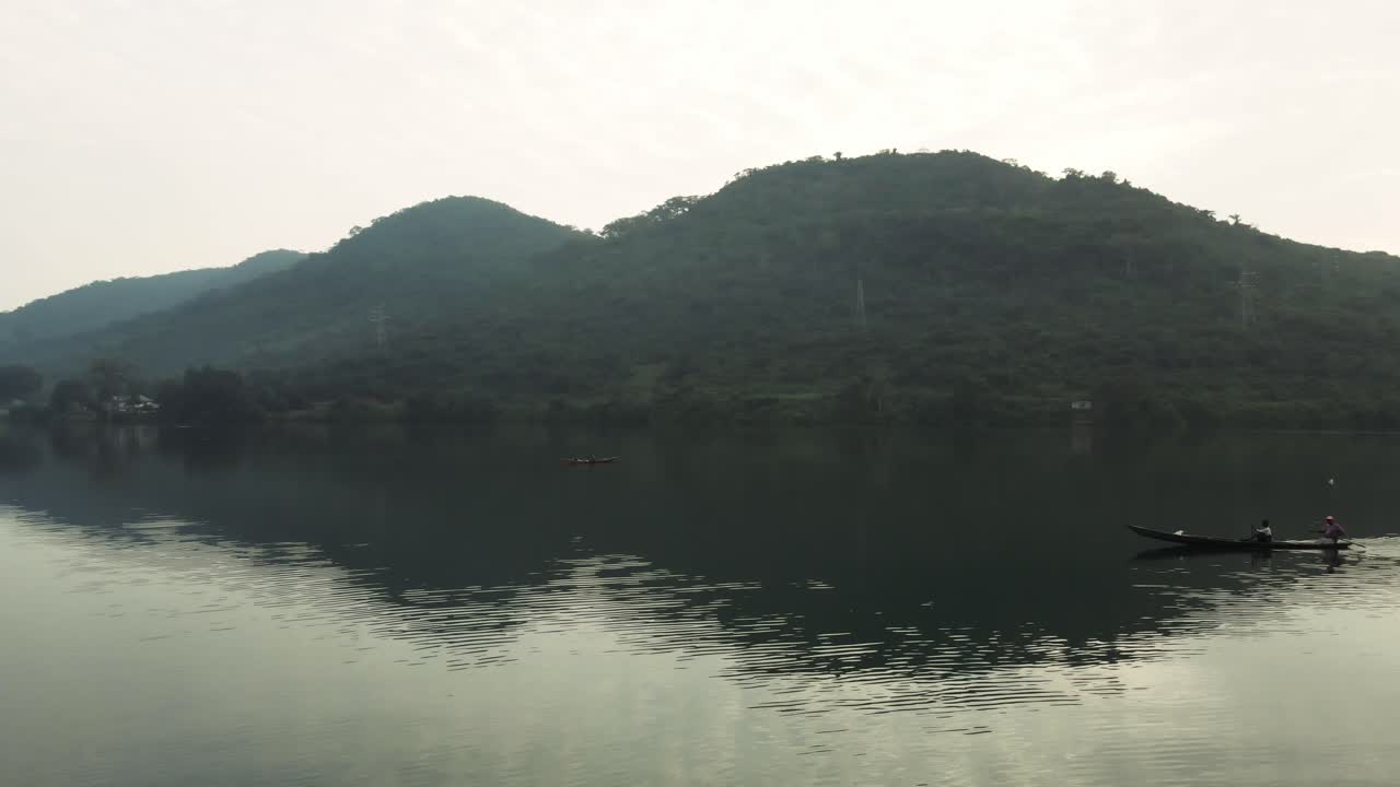 Aerial shot of fishermen doing their daily chores and boat passing by on lake at Akosombo Atimpoku, Eastern Region
