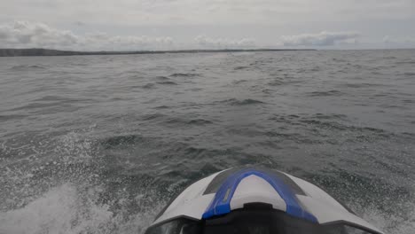 fotografía de un jinete de jet ski conduciendo a altas velocidades en un mar agitado casi cayendo