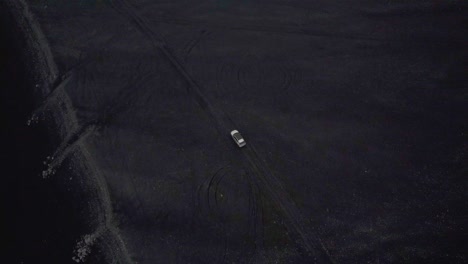 drone siguiendo un auto plateado en un camino de tierra en islandia filmando desde arriba 4k