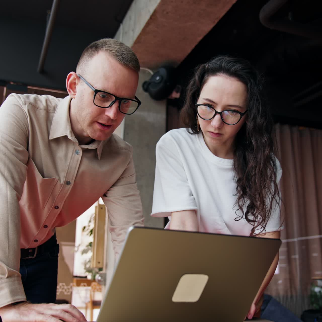 Solving problems at work. Colleagues stand bent over the laptop looking intense on the screen. Looking for the ways to find and correct a mistake. Low angle view
