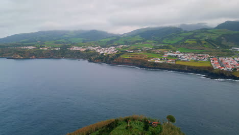 panoramic cliff coastline town on cloudy day. drone shot of blue water washing