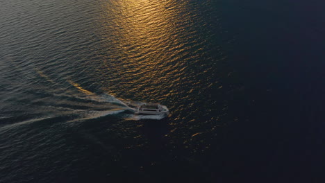 large yacht, boat cruising across garda lake, italy in warm, golden, relaxing sunset light