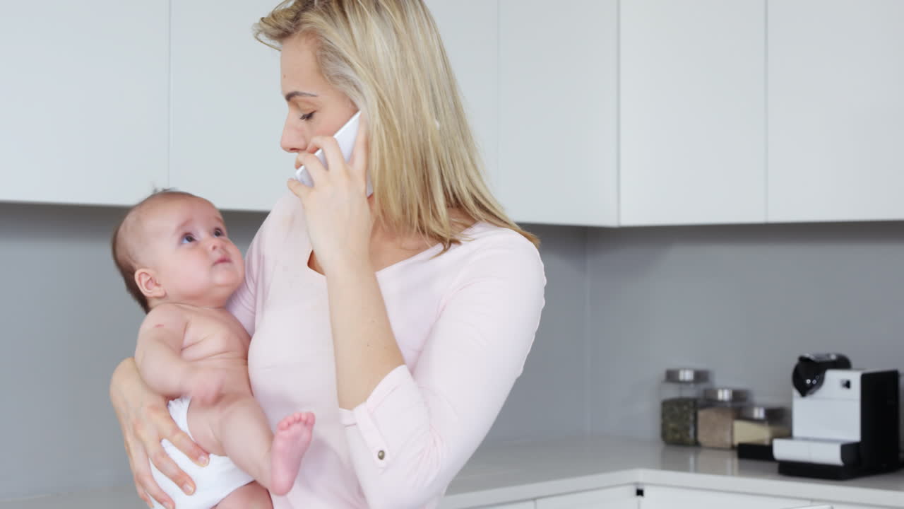 Madre che telefona mentre porta in braccio il suo bambino.
