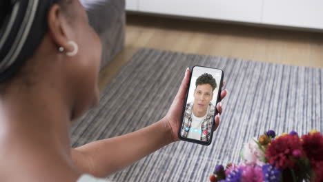 African-american-woman-holding-smartphone-with-biracial-man-on-screen