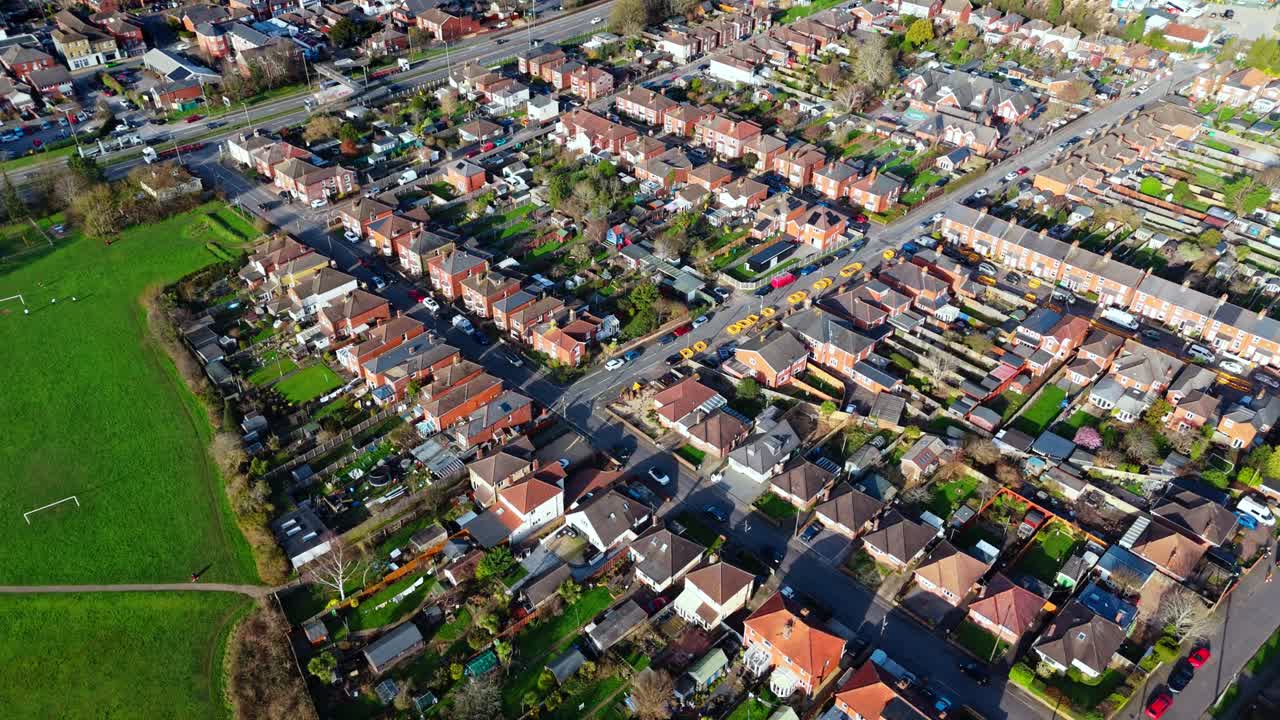 aerial panning shot over the Totton suburb west of the river in Southampton, England with cars driving the busy roads and sunlight reflecting on the blue river water with boats on it in winter