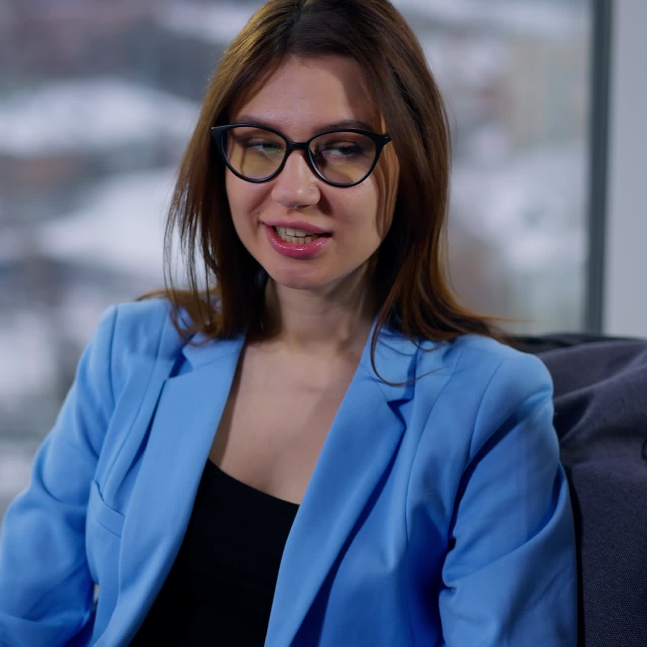 Female coworkers communicating sitting comfortably in bean bag chairs. Both ladies use modern gadgets. Blurred backdrop