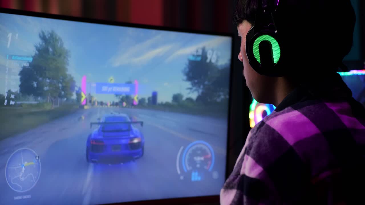 헤드폰을 착용하고 컴퓨터에서 비디오 게임을 하고, 레이싱 비디오 게임을 하는 아시아 십대 소년 게이머의 클로즈업