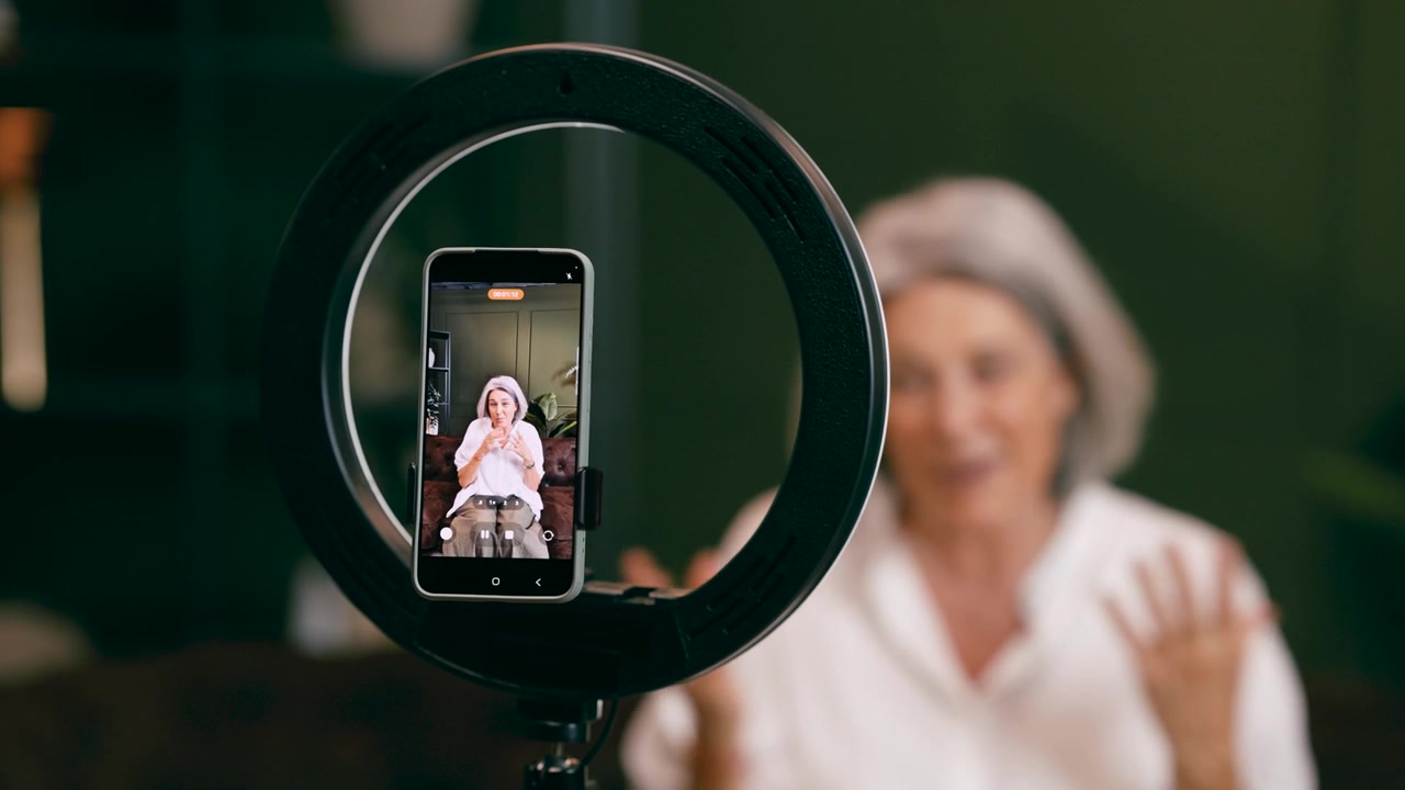 Donna matura che registra contenuti video con lo smartphone e una luce ad anello