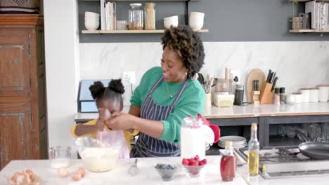 madre y hija afrodescendientes felices preparando masa en un cuenco en la cocina, cámara lenta