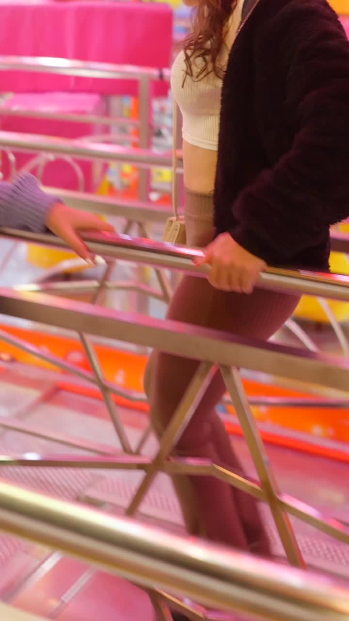 Donna che cammina attraverso la coda di un parco divertimenti con giostre colorate